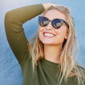 Eine blonde lachende Frau mit Sonnenbrille.