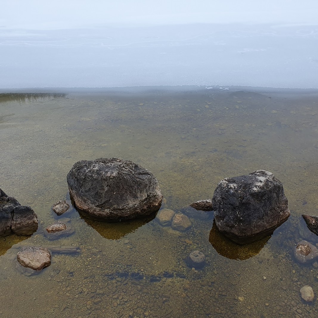 Steine liegen am Ufer eines Sees.